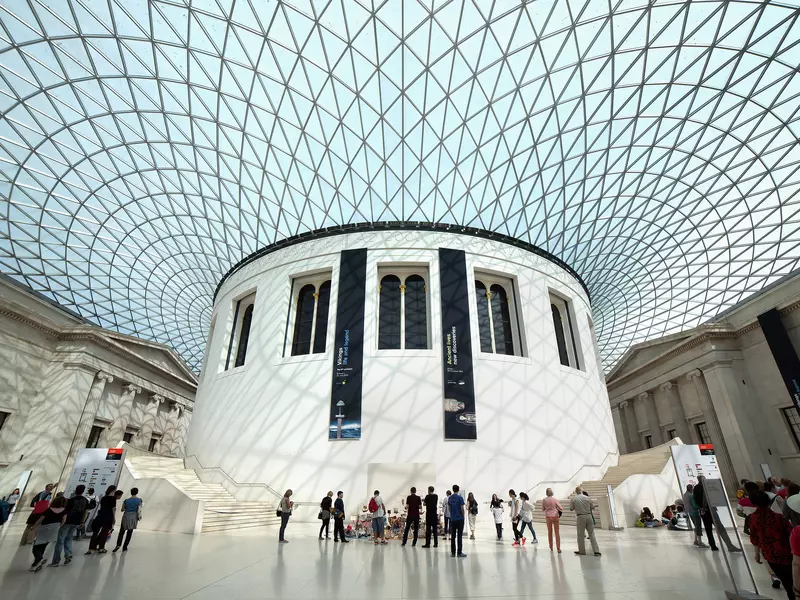 People stand inside the cavernous and modern interior of the British Museum in London. 