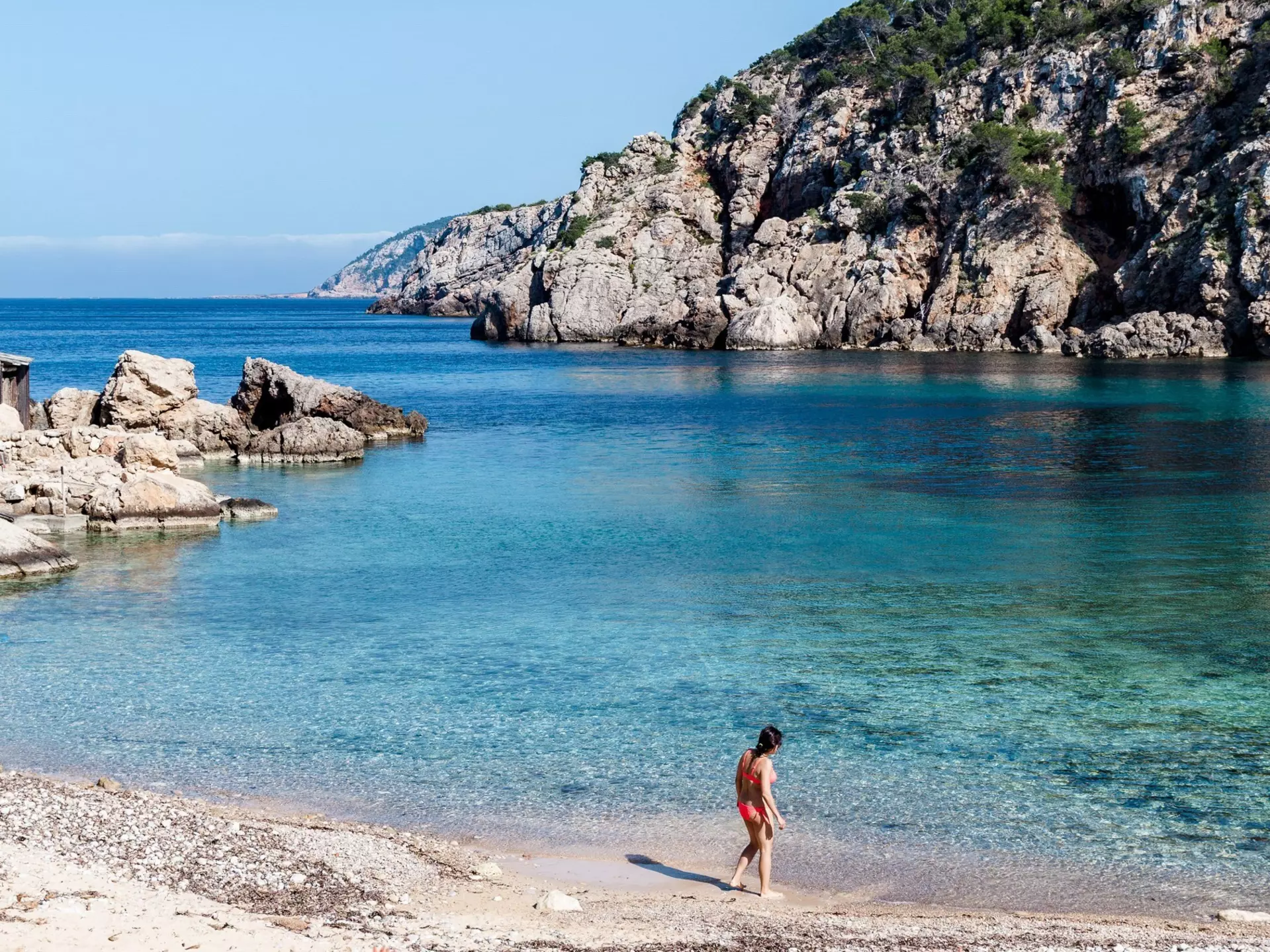 A woman checks the water at the secluded Cala d’en Serra beach on Ibiza’s northern shore.