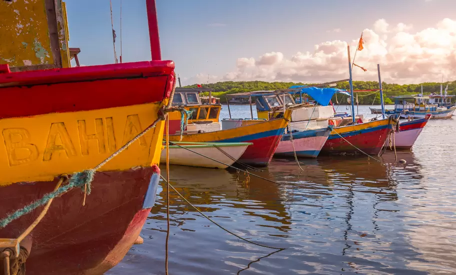 Bahia, Brazil: red and yellow wooden fishing boats moored on a calm river, one hull painted 'BAHIA', mangroves behind