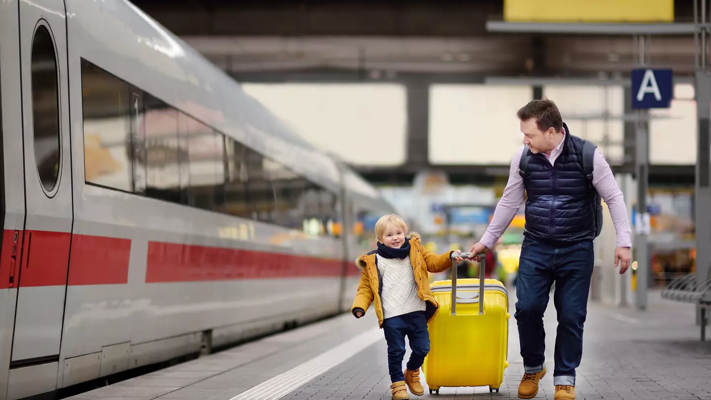 Smiling little boy and his father waiting express train on railway station platform
