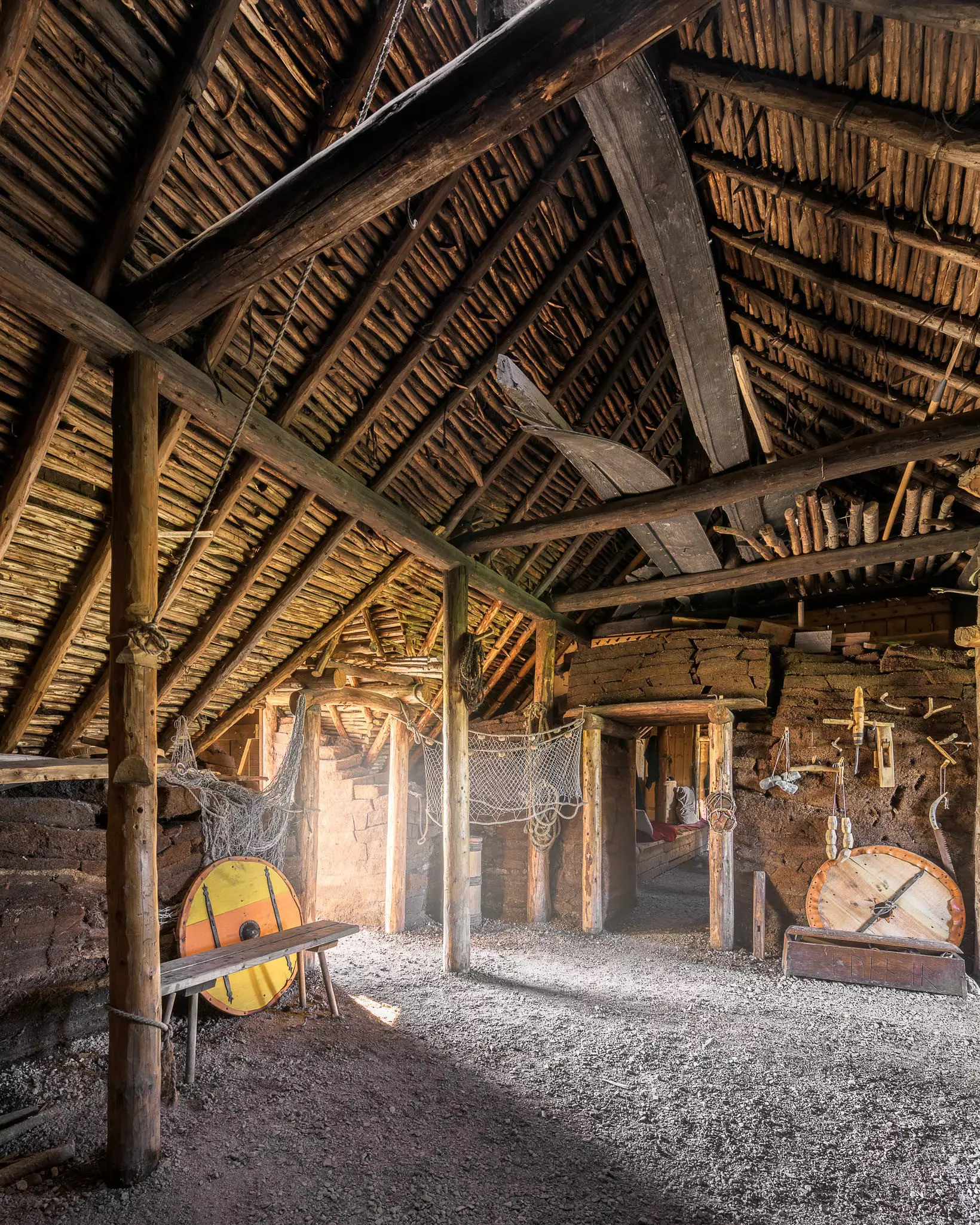 Interior of a wooden structure with a dirt floor and circular shields
