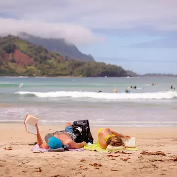 Reading on the beach in Hanalei Bay, Kaua'i. bluestork/Shutterstock