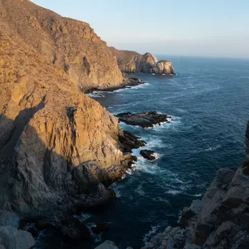 Scenic view of rugged cliffs meeting the ocean at Punta Lobos, Baja California, under a clear blue sky during sunset., License Type: media, Download Time: 2026-01-21T16:23:37.000Z, User: LP_YKhanna, Editorial: false, purchase_order: 65050 - Digital Destinations and Articles, job: LP, client: App Content, other: Yuvraj Khanna