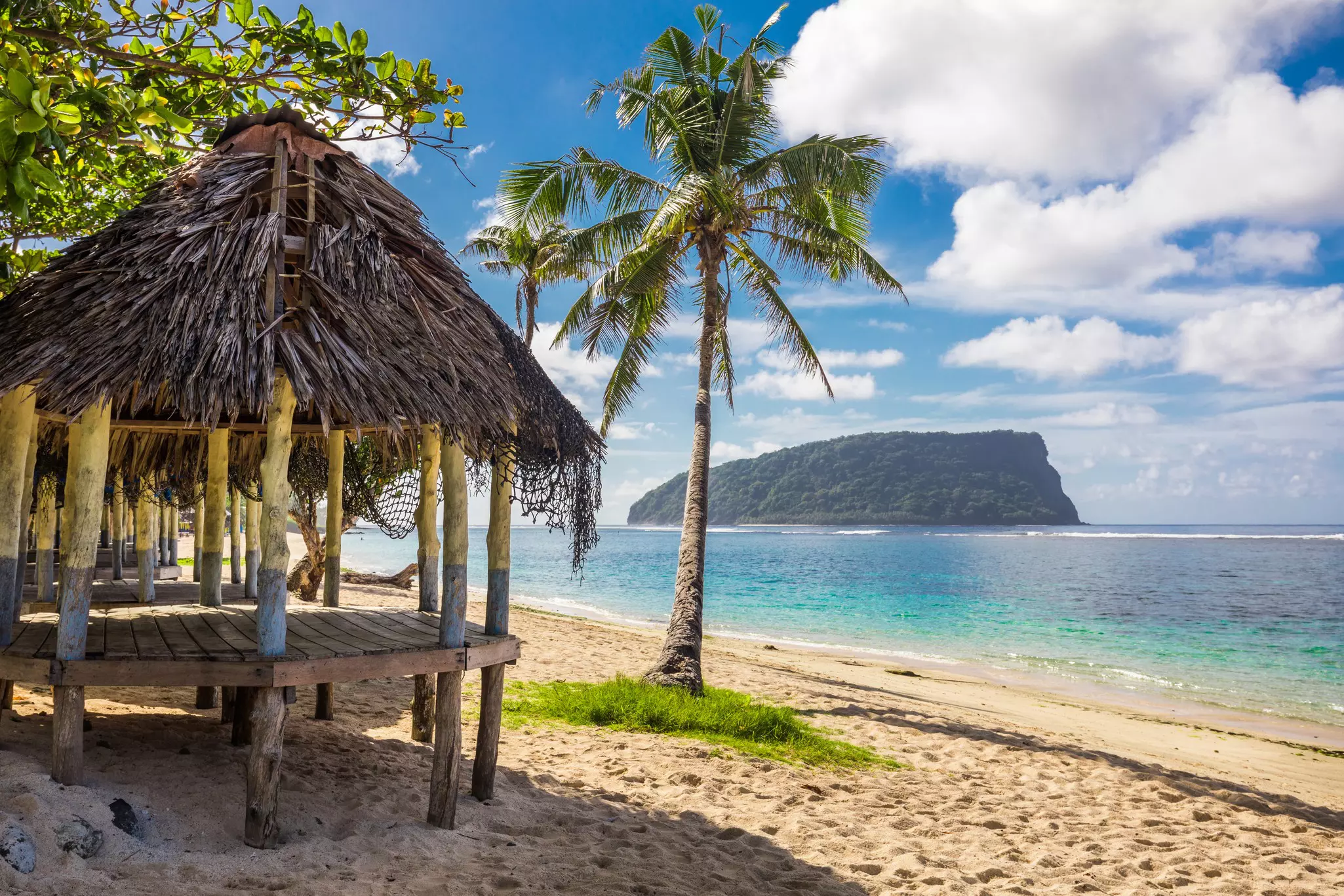 An open-sided thatched hut on a sandy glorious beach.