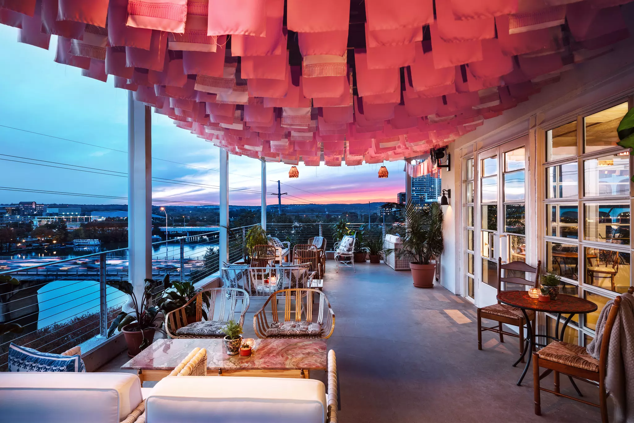 Bar deck with a view of a bridge. The deck has rectangular and round tables, and a variety of wicker and cushioned chairs