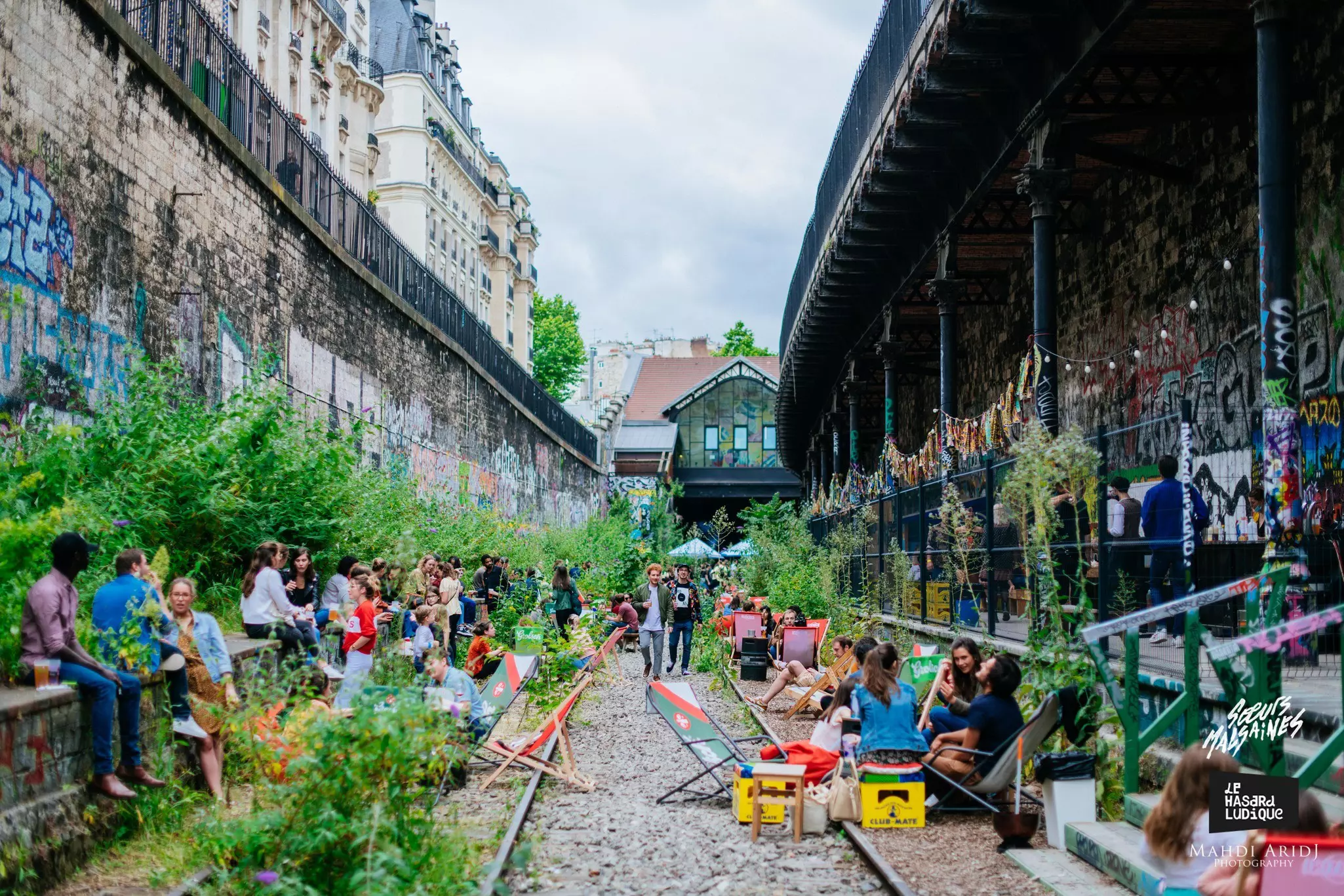 A hiker carrying a backpack crosses a boardwalk over a stream on a rural walking route on a sunny day.
