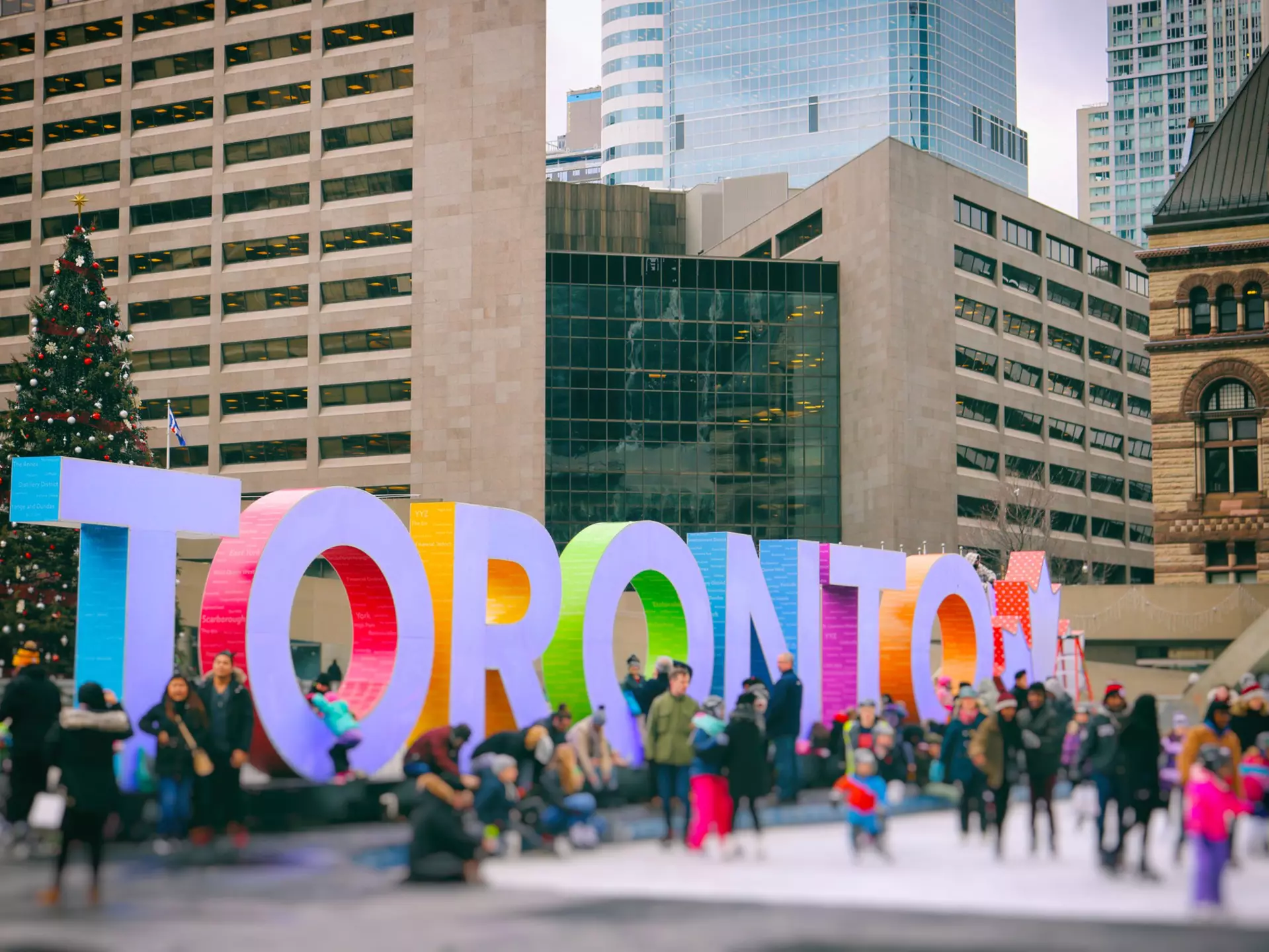 Lots of people are having fun by the colourful Toronto sign at Nathan Phillips Square.
