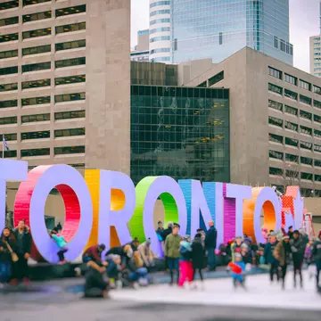 Lots of people are having fun by the colourful Toronto sign at Nathan Phillips Square.