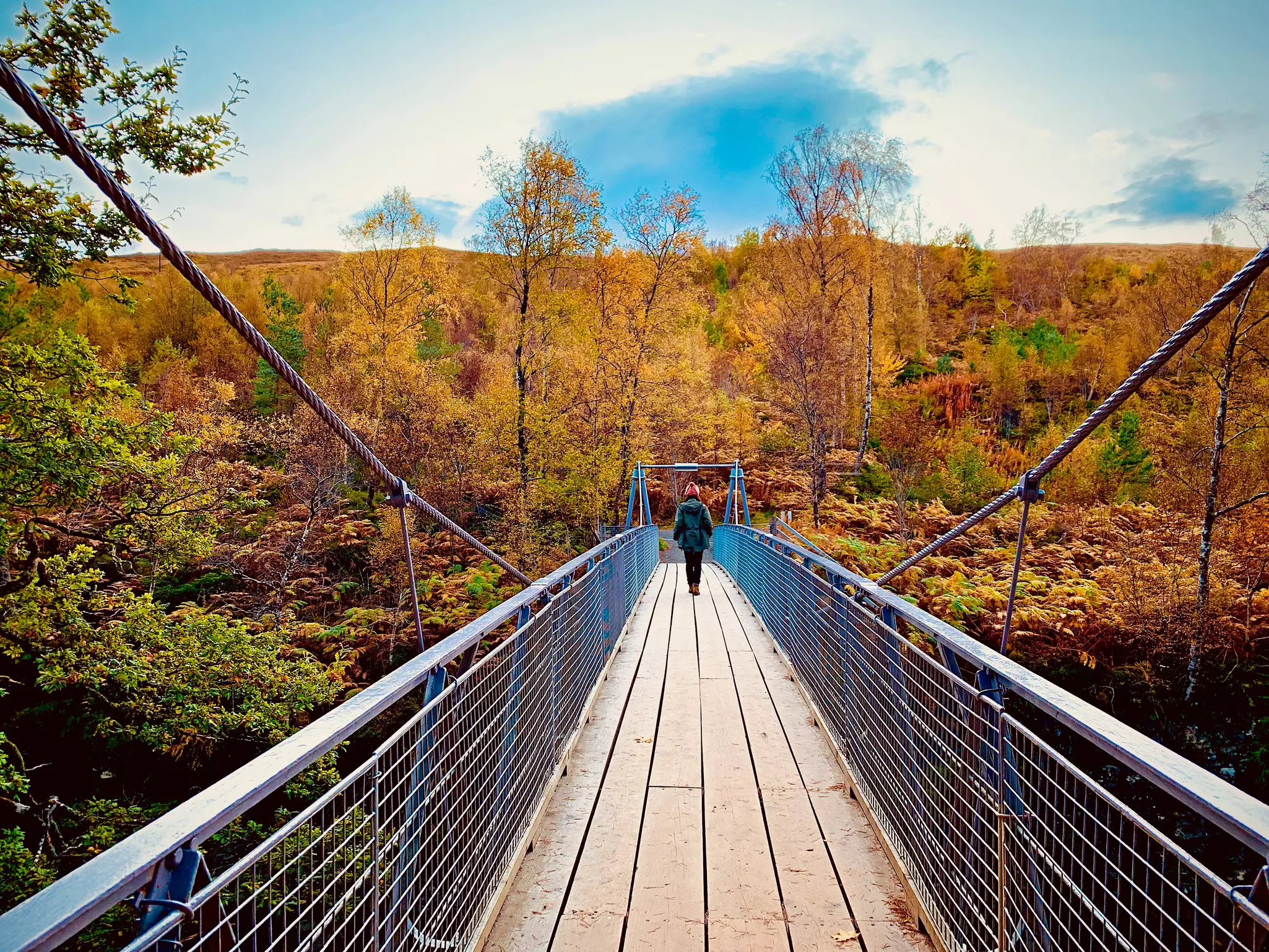 A young woman walks on a suspension bridge at Corrieshalloch Gorge in Scotland.