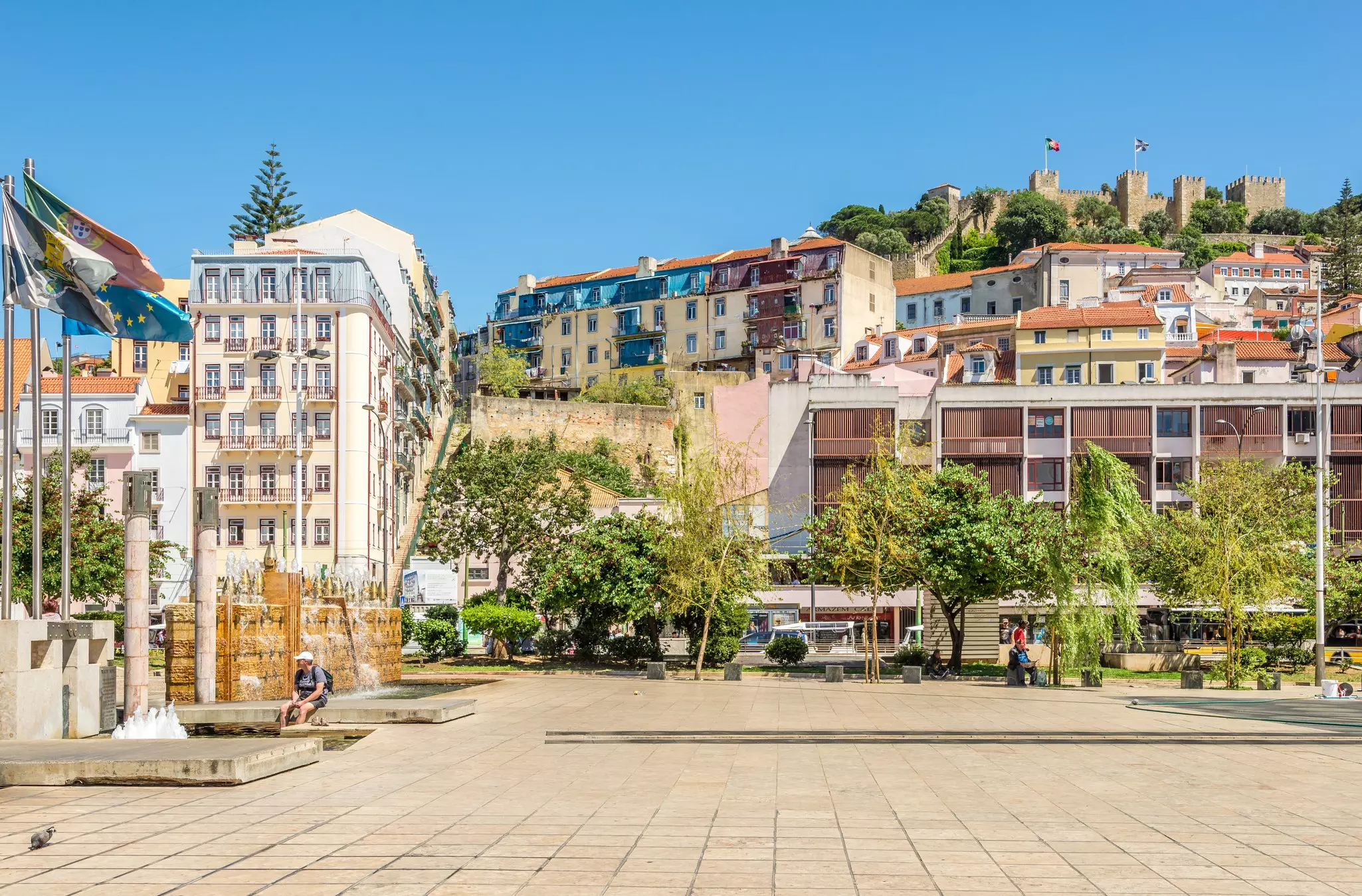 A large hilltop castle overlooks a city square.