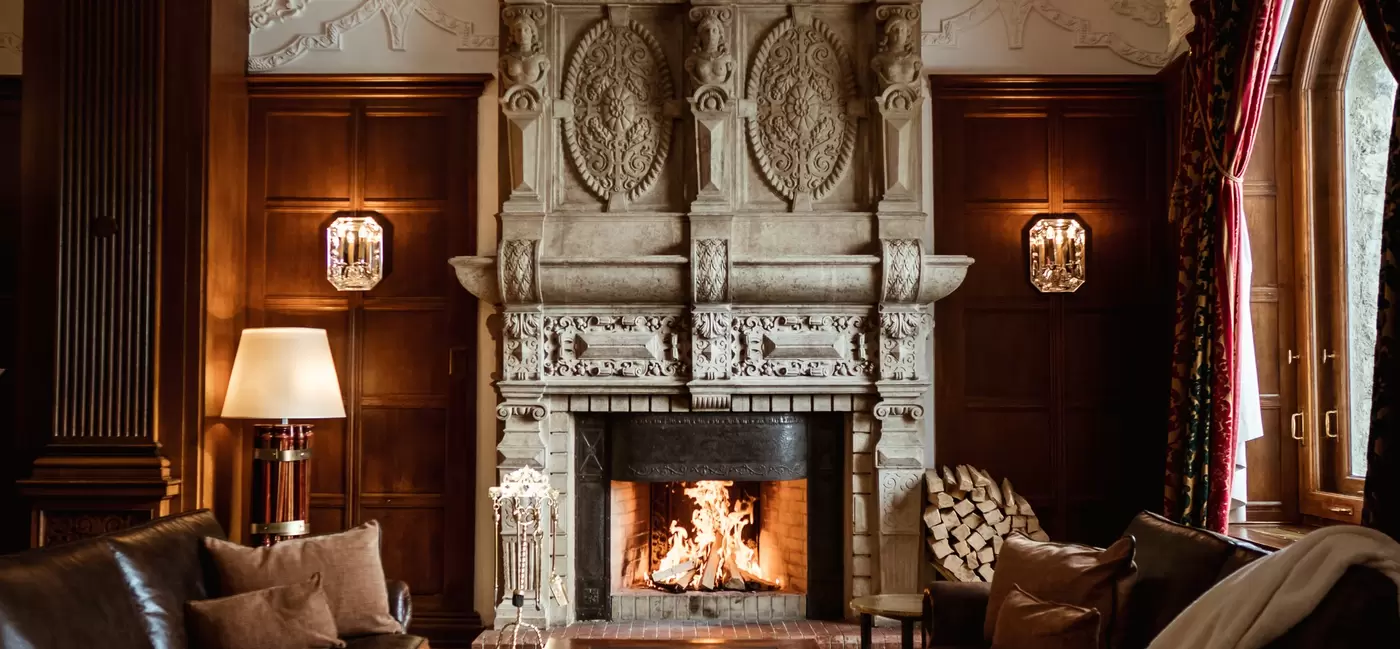Leather couches face each other in front of a roaring fire.