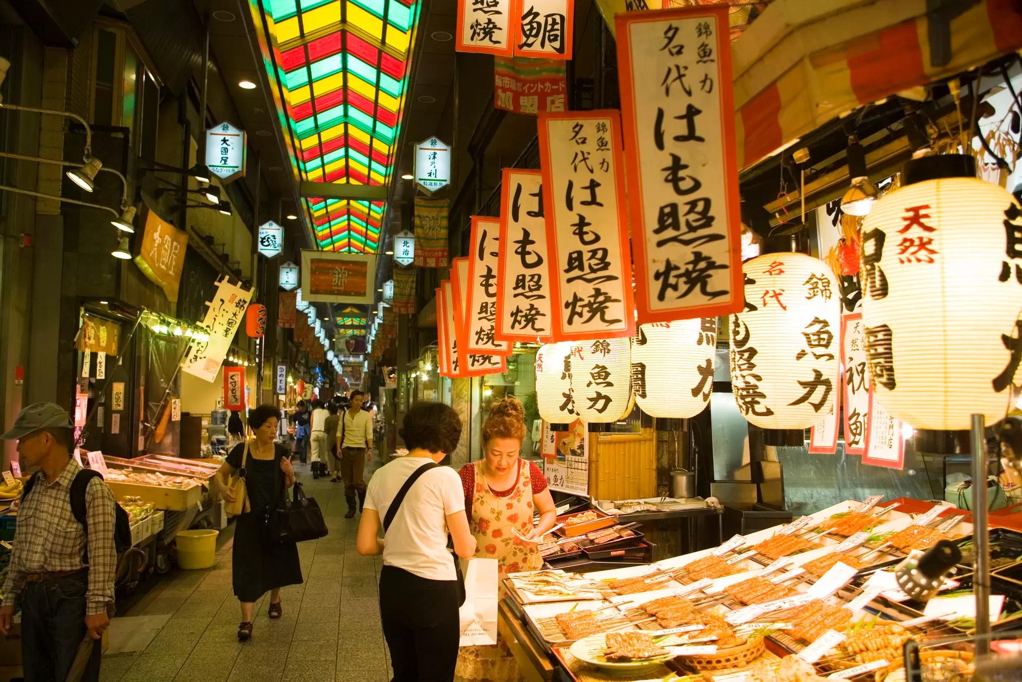 A stall with lanterns and Japanese-language signs at Nishiki Market, Kyoto, Japan.