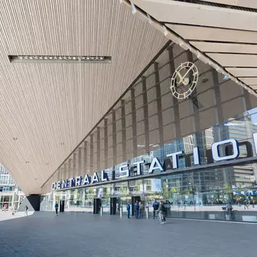 A wood-slatted canopy and clock over the station's glass entrance and sign.