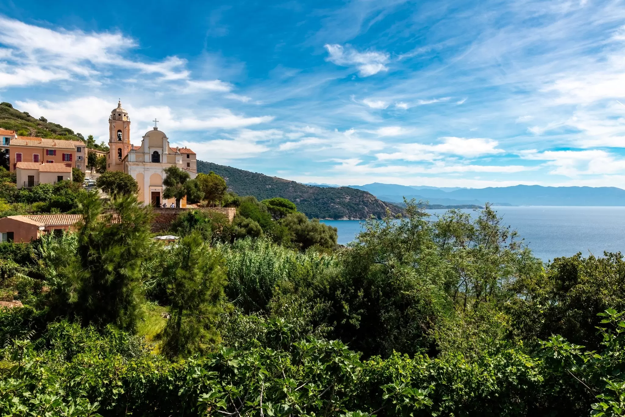 A small church stands tall above the ocean in a hilltop village in Cargèse, Corsica.