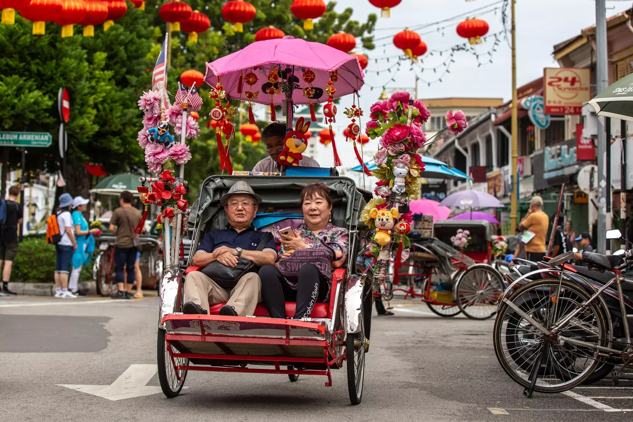Unidentified people getting pedaled on a trishaw bicycle taxi through the busy streets of George Town, Penang, Malaysia