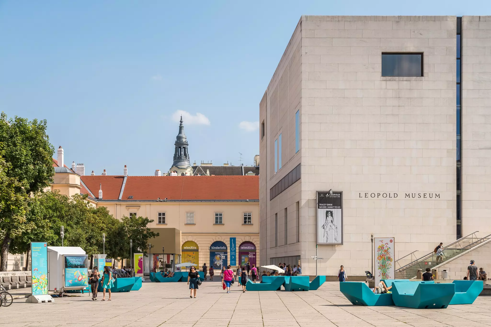 A plaza with turquoise green structures in front of a museum in Vienna.