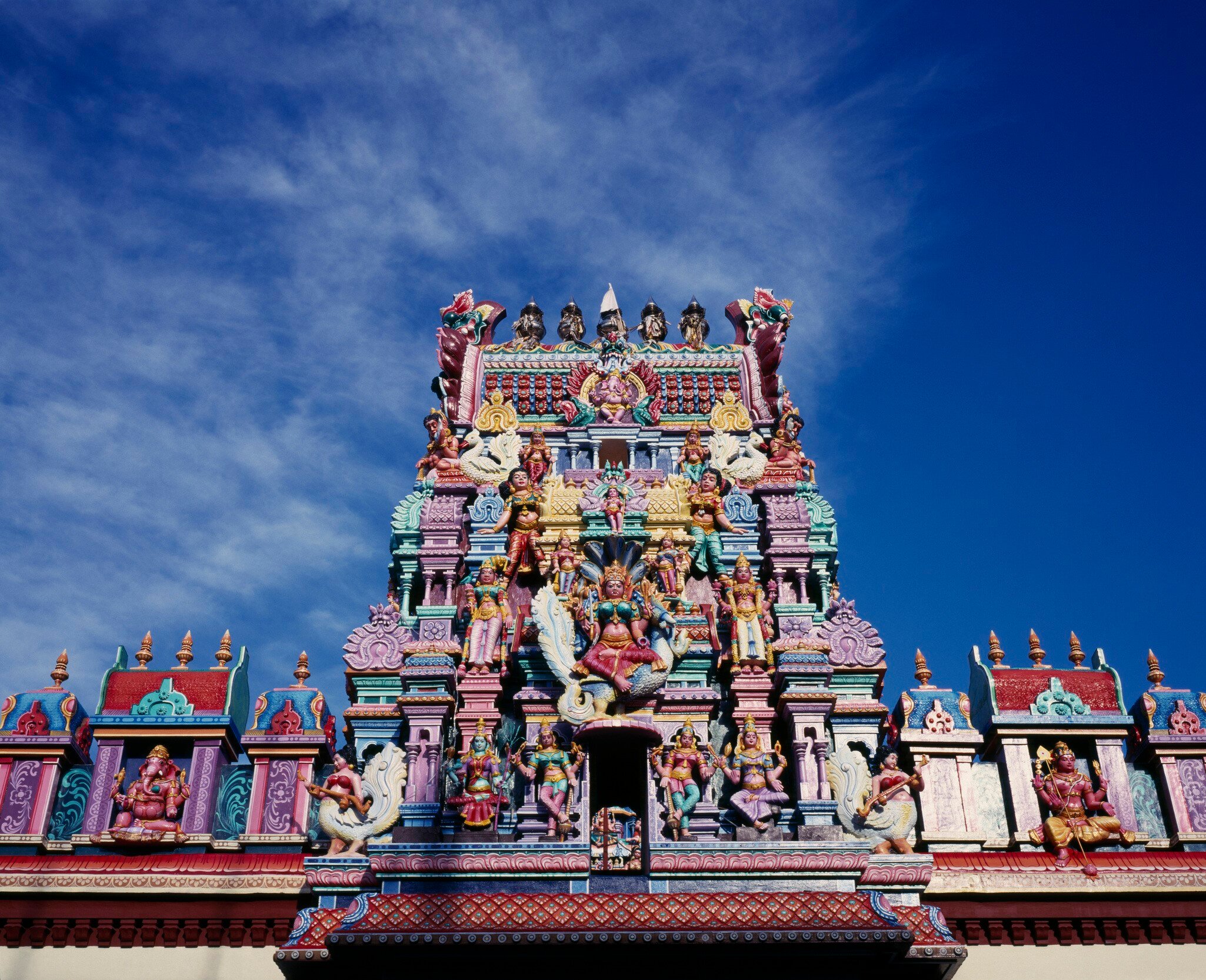 malaysia, penang, georgetown, sri mariamman temple. part view of exterior roof and gopuram painted tower decorated with brightly painted figures of hindu gods and characters.