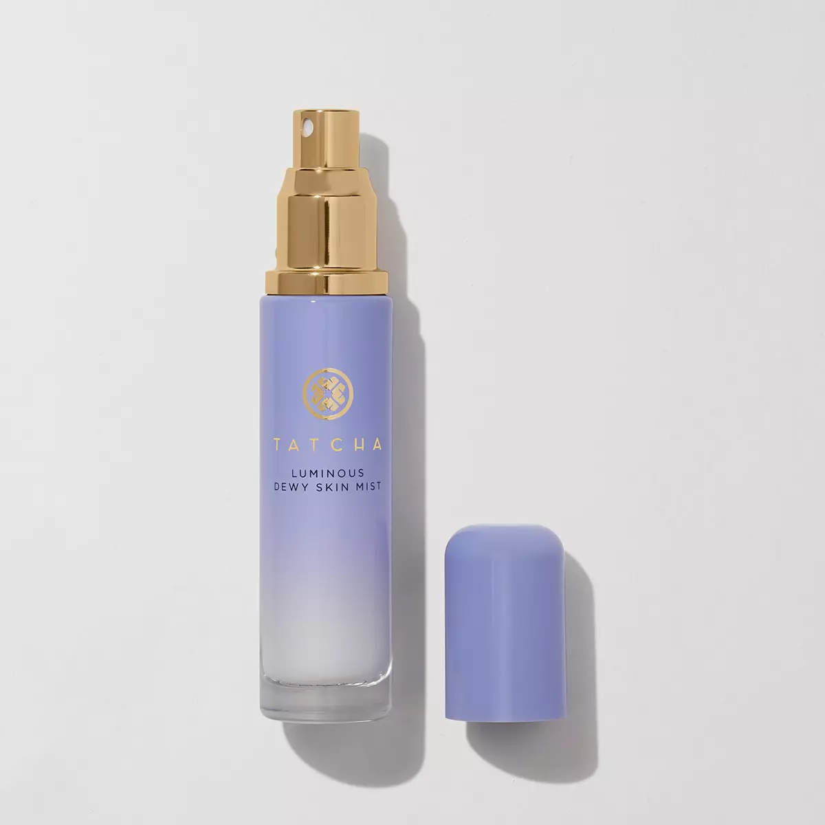 A purple bottle of skin mist with a brass atomizer