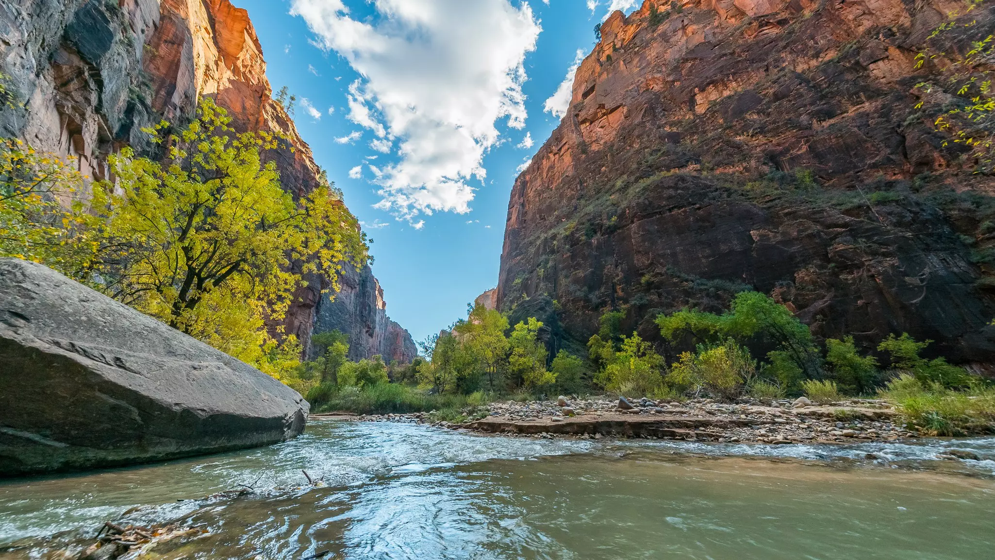 A river flowing through a red-rock canyon with bright blue sky above