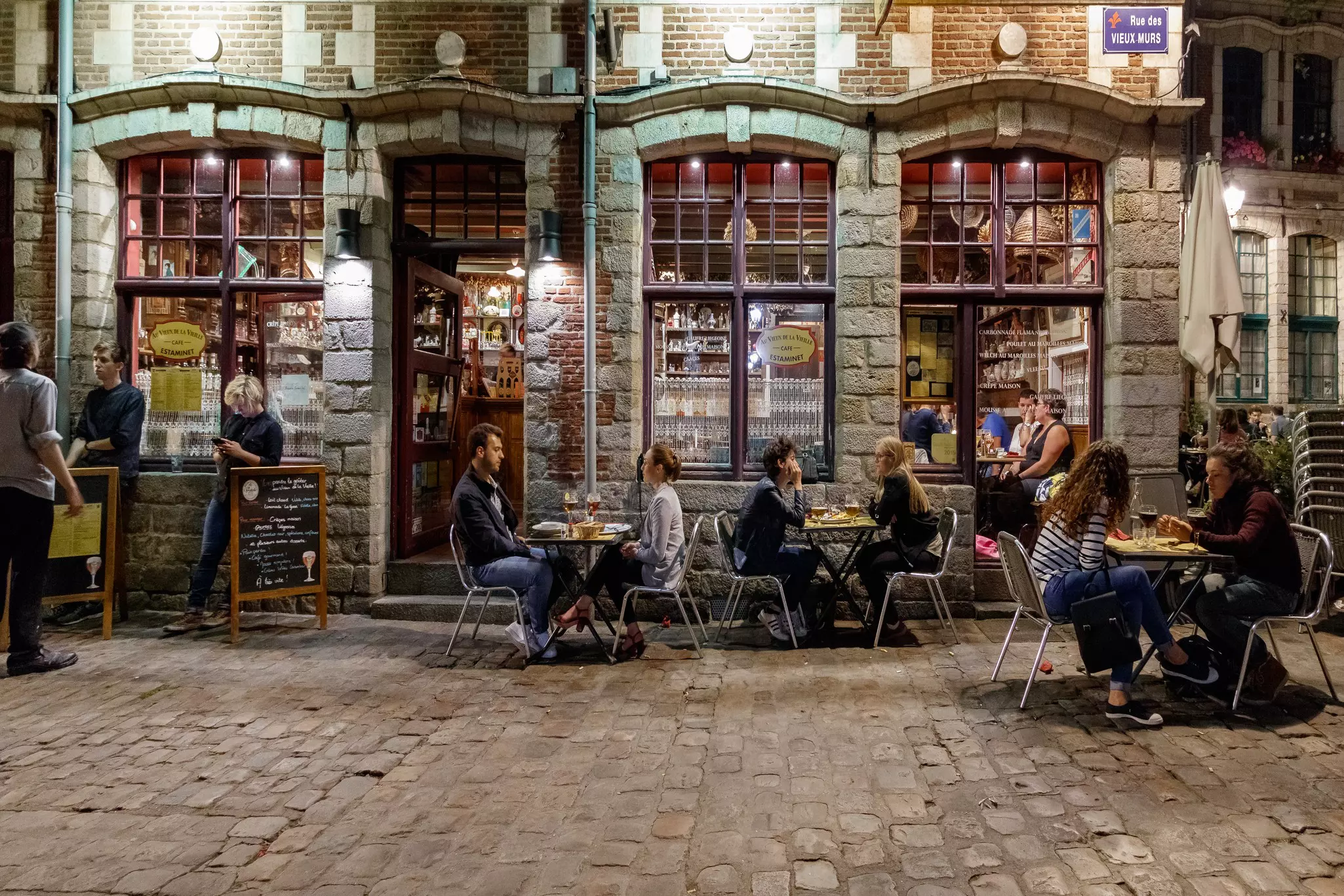 People sit outside a traditional French bar in the evening in Lille.