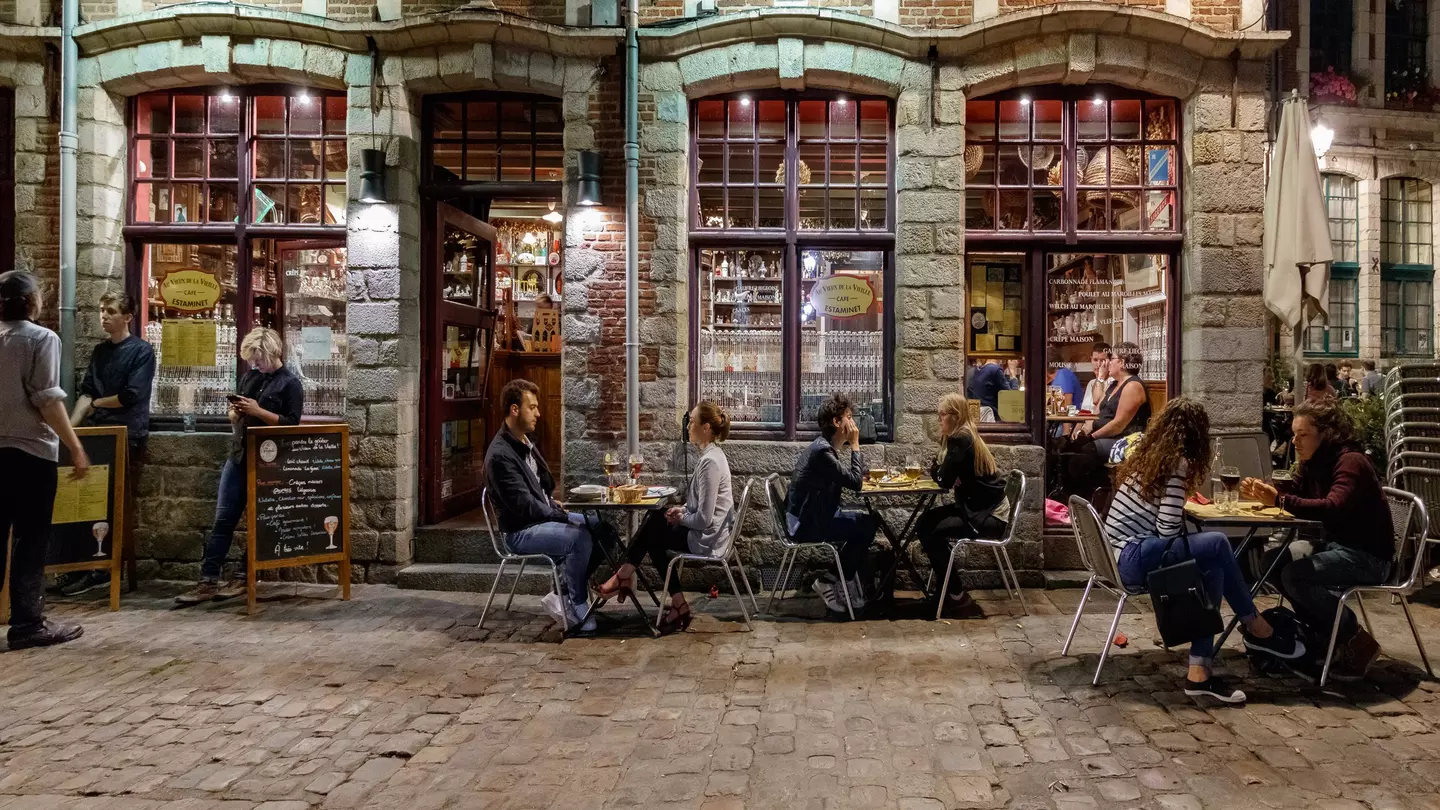 People sit outside a traditional French bar in the evening in Lille.