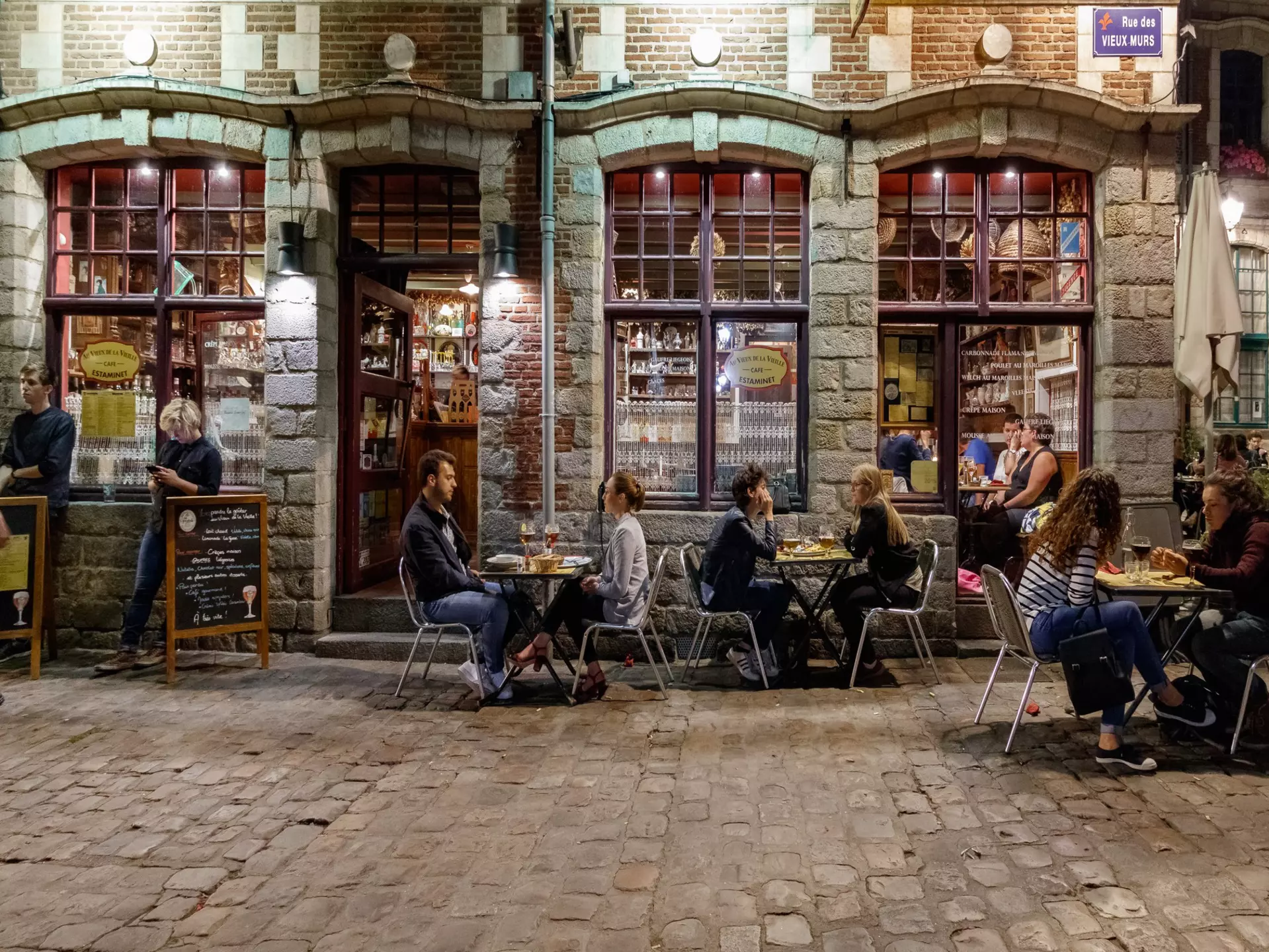 People sit outside a traditional French bar in the evening in Lille.