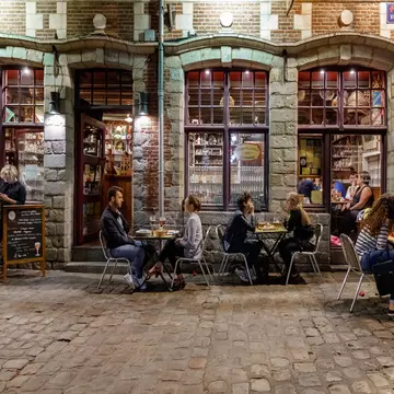People sit outside a traditional French bar in the evening in Lille.