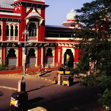 Yellow-and-black auto-rickshaws on the road in front of a red station building with white domes, Egmore, Chennai.