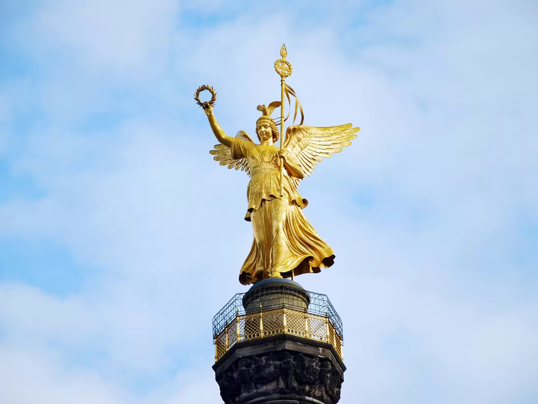Gold angel sculpture of the Siegessaeule victory column with blue sky in the background in Berlin, Germany.