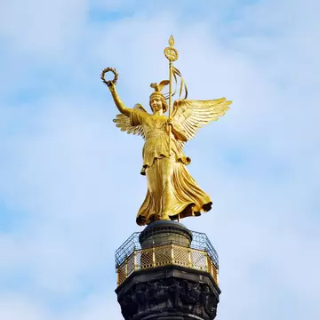 Gold angel sculpture of the Siegessaeule victory column with blue sky in the background in Berlin, Germany.