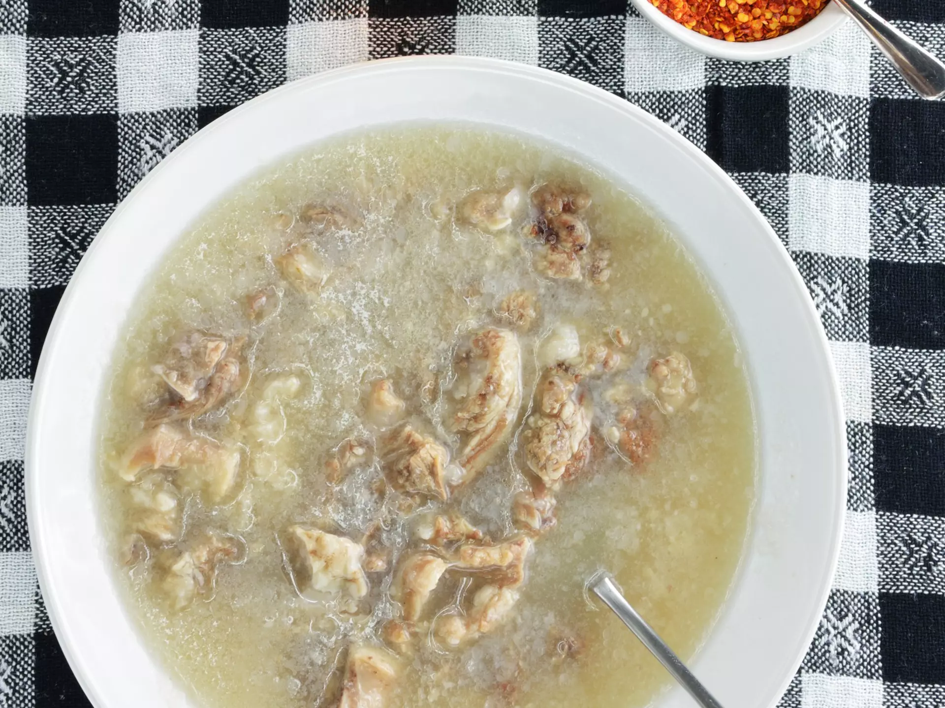 A bowl of soup on a black-and-white checked tablecloth
