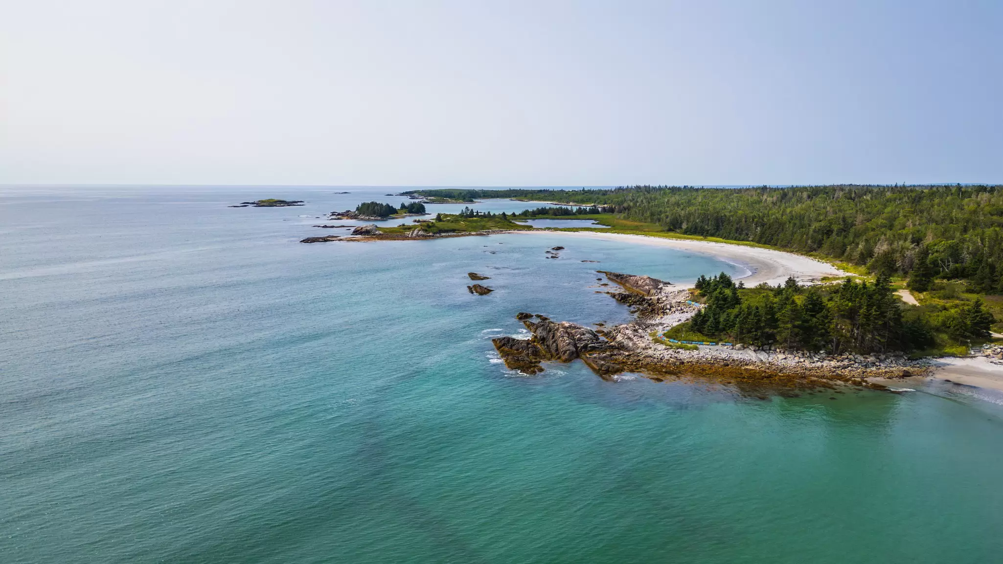 A curve of beach backed by forest.