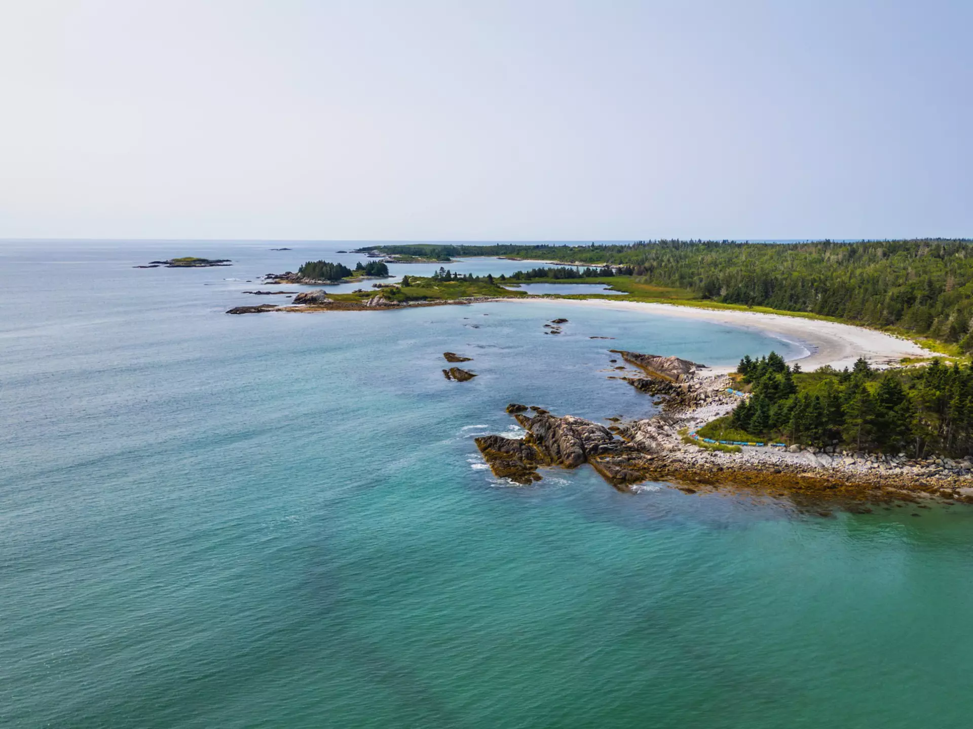 A curve of beach backed by forest.