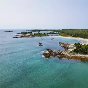 A curve of beach backed by forest.