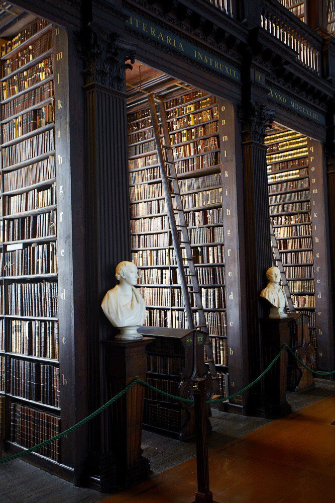 Bookshelves in Long Room at Trinity College Library lined with marble busts. Dublin, Ireland.