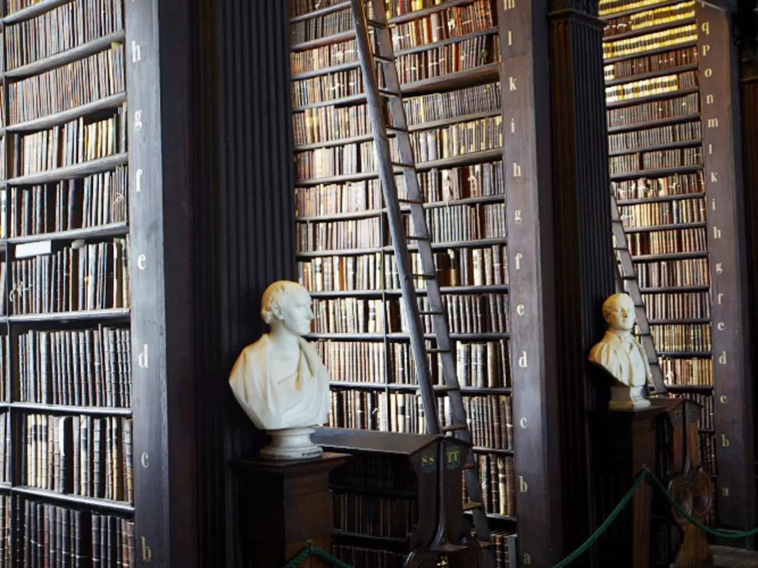 Bookshelves in Long Room at Trinity College Library lined with marble busts. Dublin, Ireland.