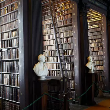 Bookshelves in Long Room at Trinity College Library lined with marble busts. Dublin, Ireland.