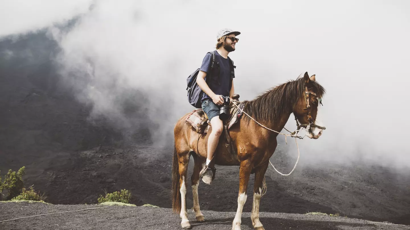 Young man on horseback trekking up Pacaya volcano, Antigua, Guatemala