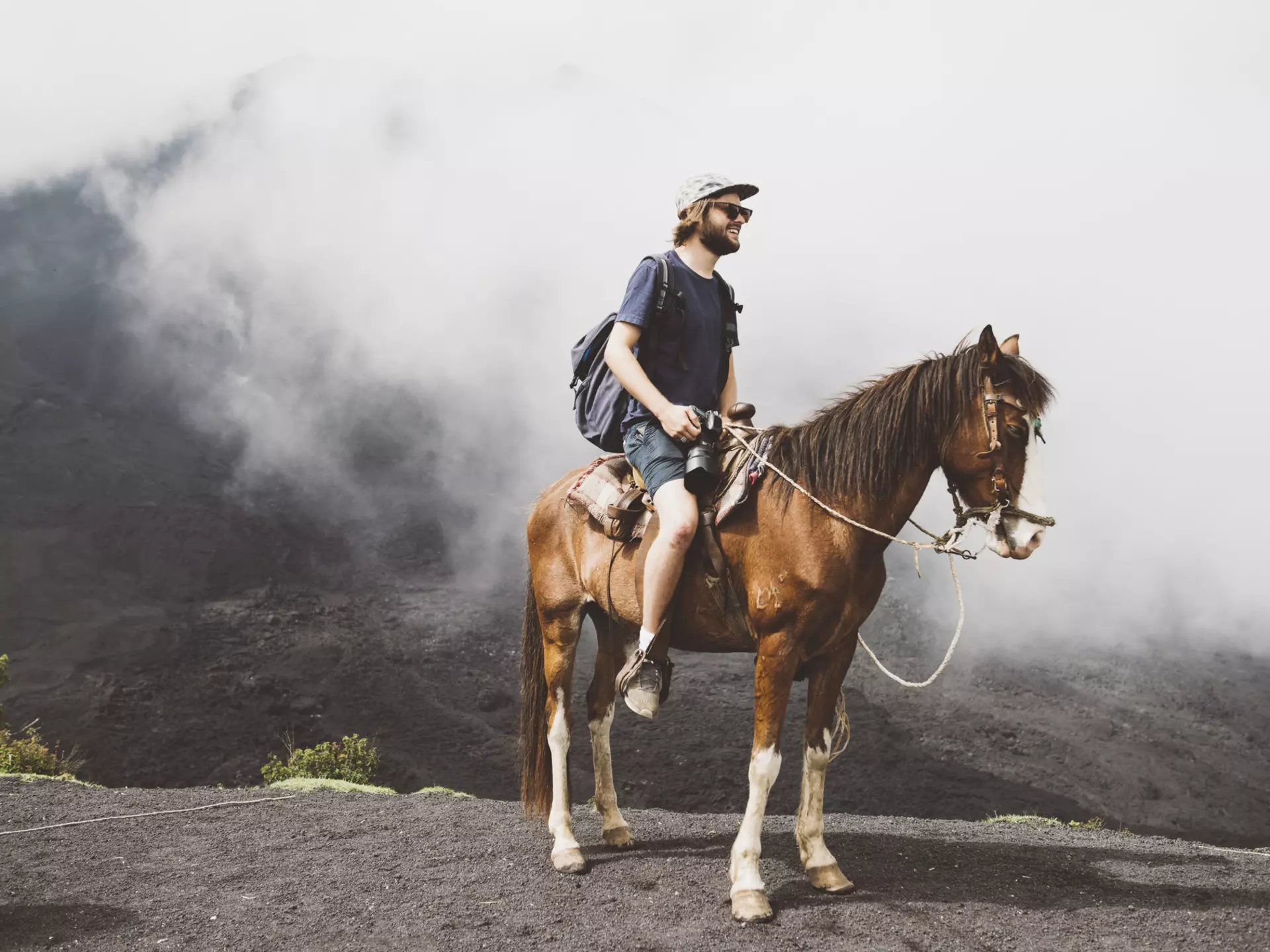 Young man on horseback trekking up Pacaya volcano, Antigua, Guatemala