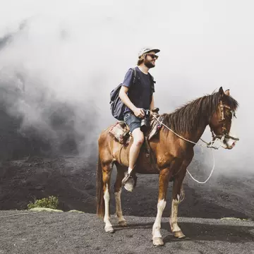 Young man on horseback trekking up Pacaya volcano, Antigua, Guatemala