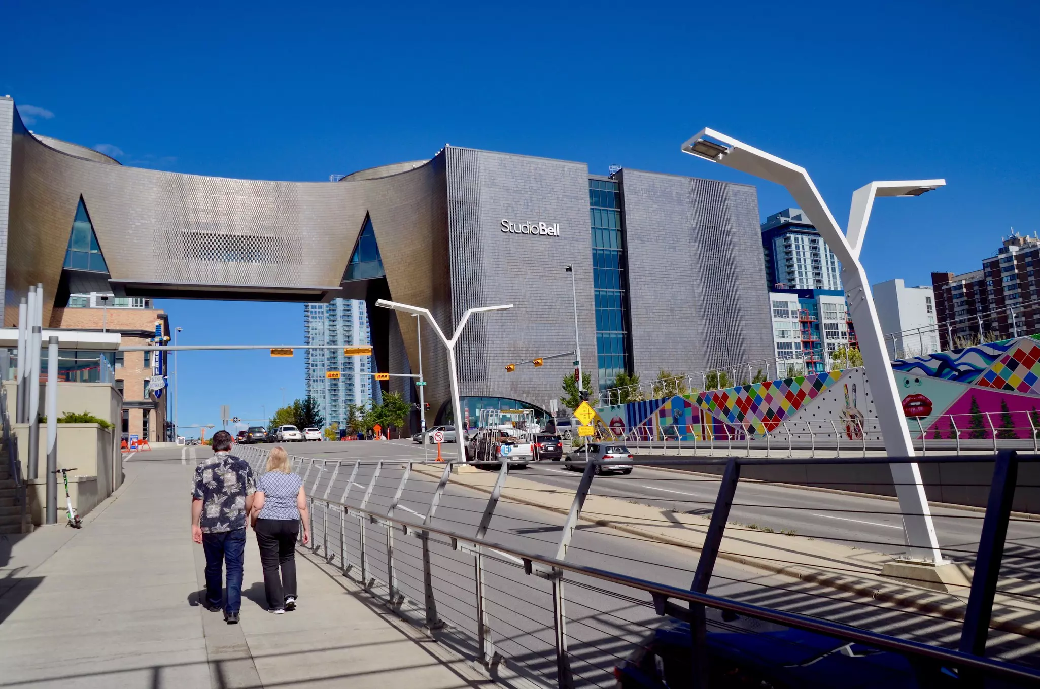 Two women walk on a city street toward an ultra-modern building