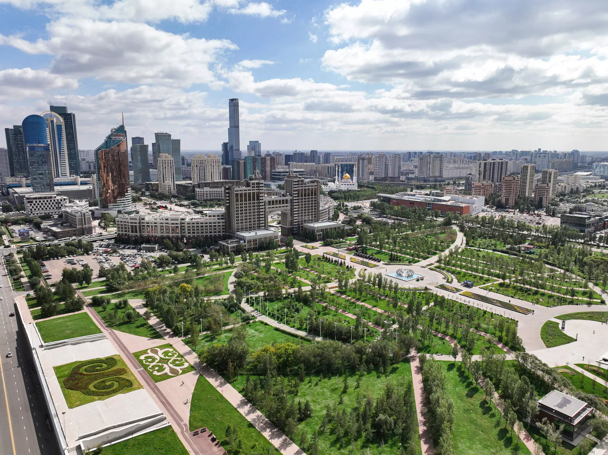 A landscaped city park backed by a high-rise city of steel-and-glass skyscrapers.
