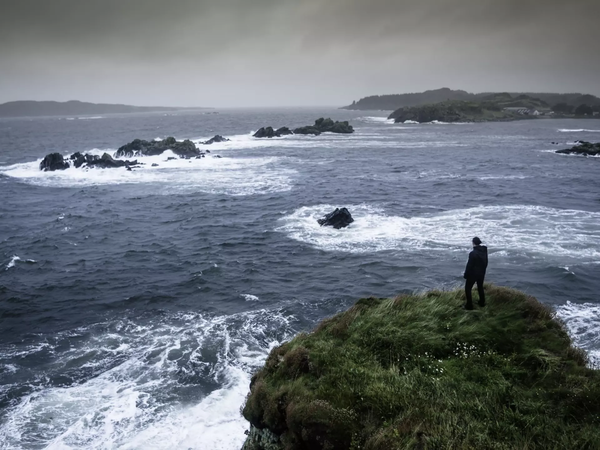 Woman standing on a cliff looking out to sea on the Isle of Islay, Scotland