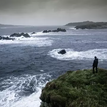 Woman standing on a cliff looking out to sea on the Isle of Islay, Scotland
