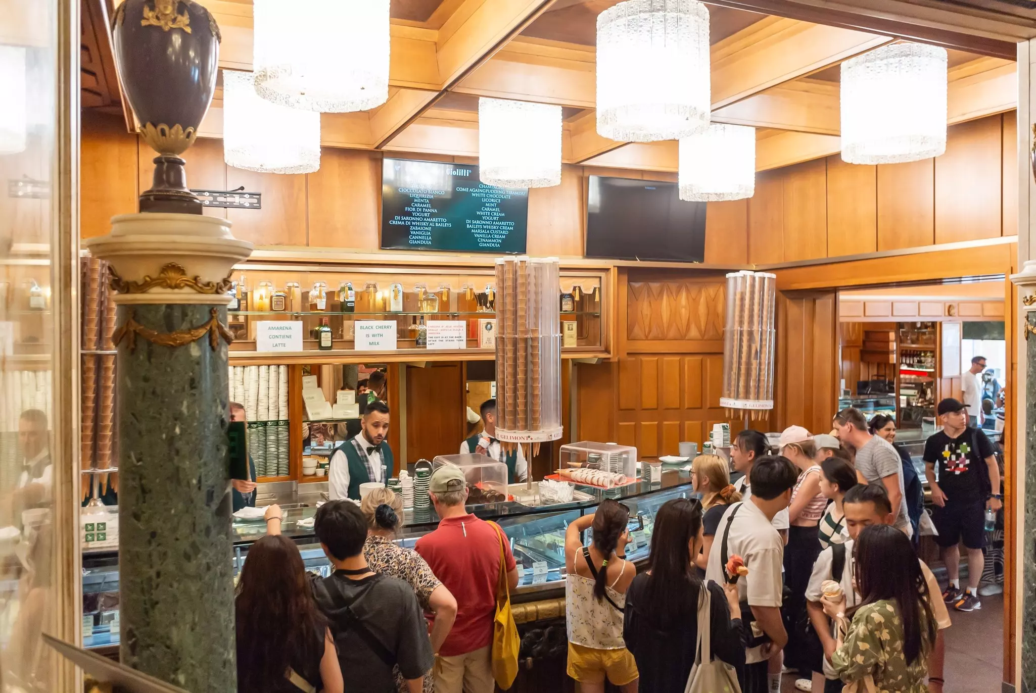People line up at the counter of a ice cream shop in a historic buildling.