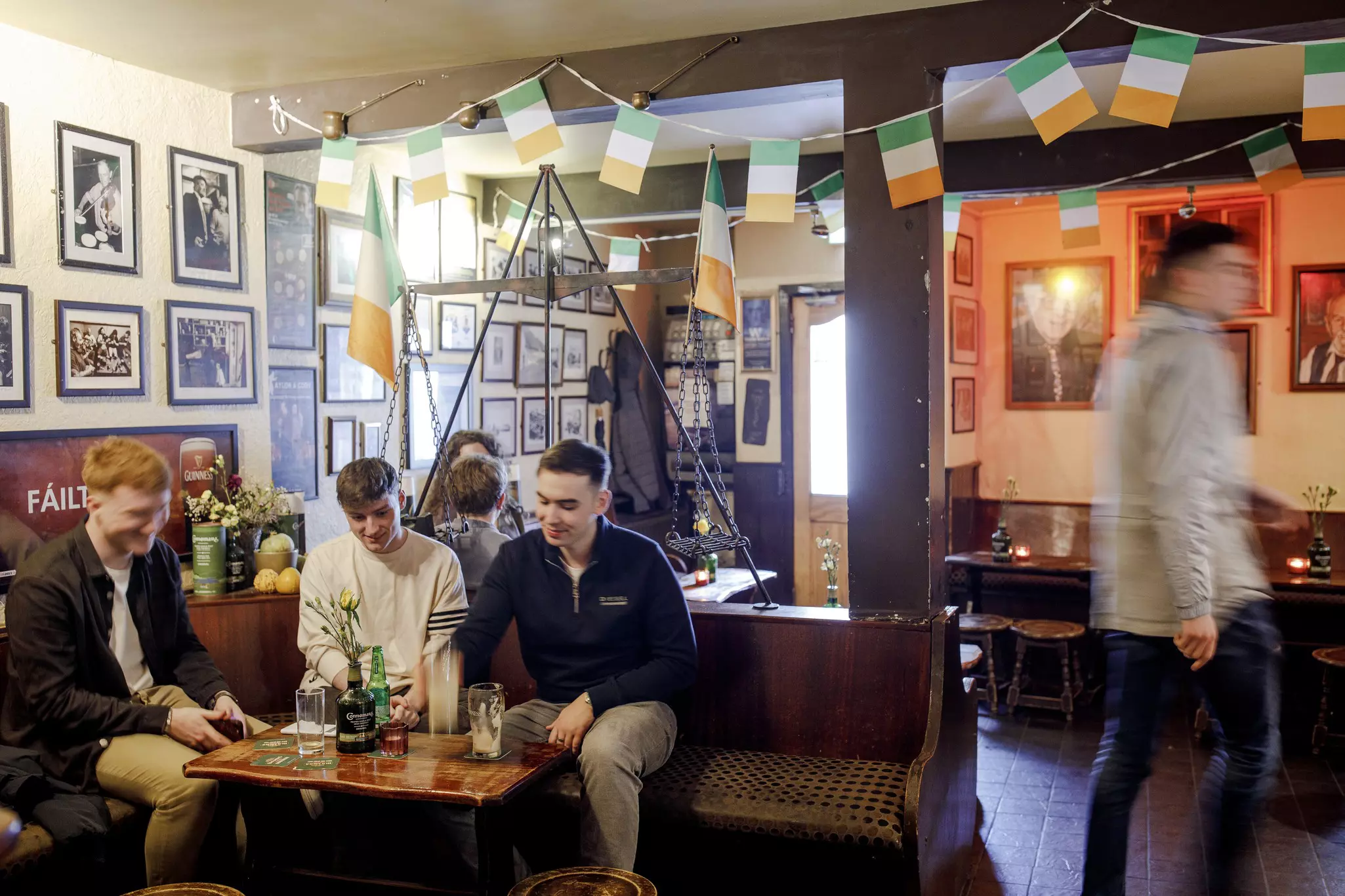 People sitting in a pub in Galway with bunting in the colors of the Irish flag overhead.
