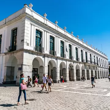 Locals and tourist passing a colonial building at the Plaza San Martin in the center of town. Cordoba, Argentina.