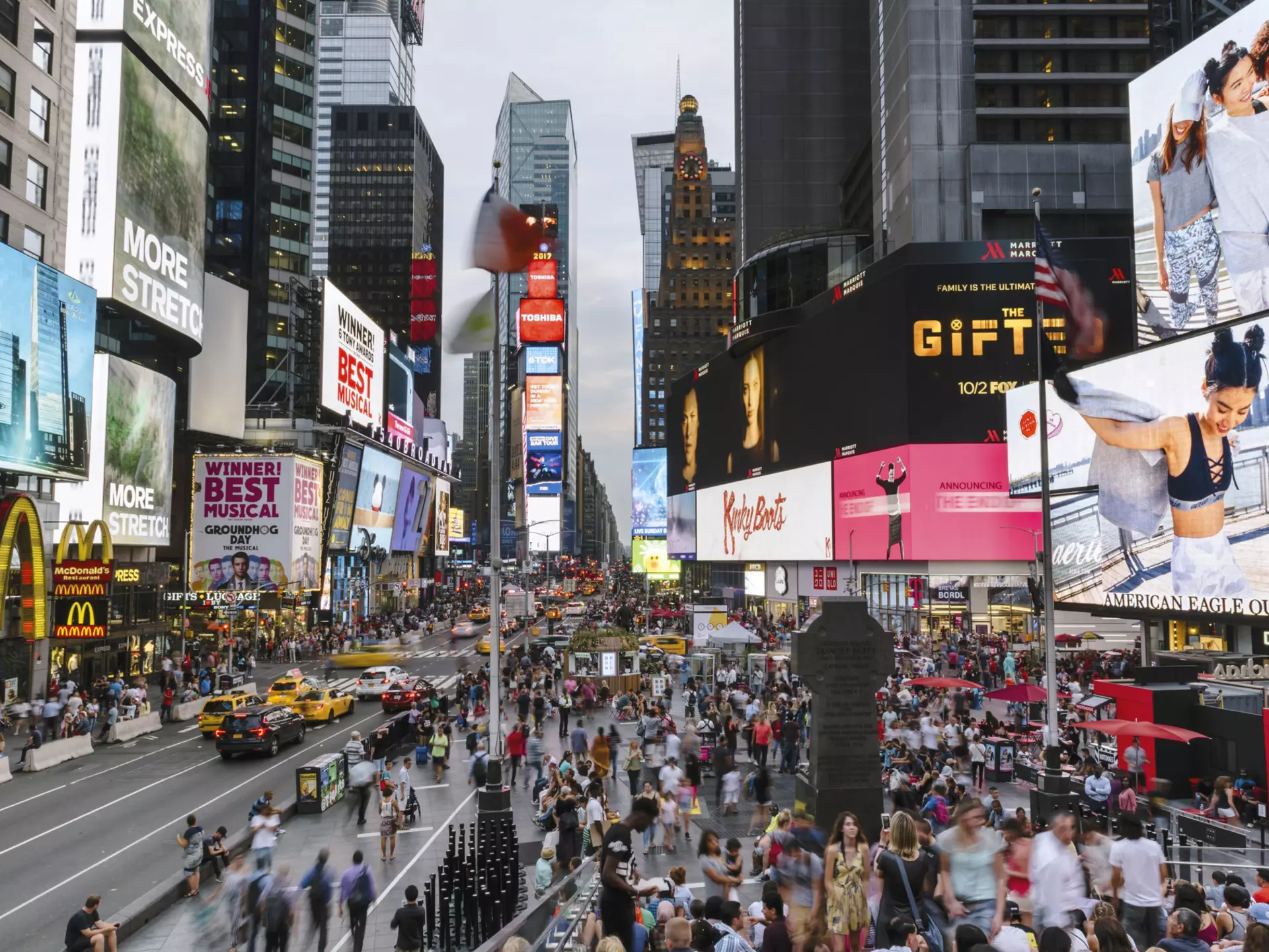 Crowds of people fill Times Square at low light.