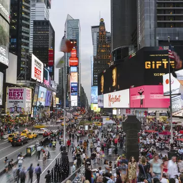 Crowds of people fill Times Square at low light.
