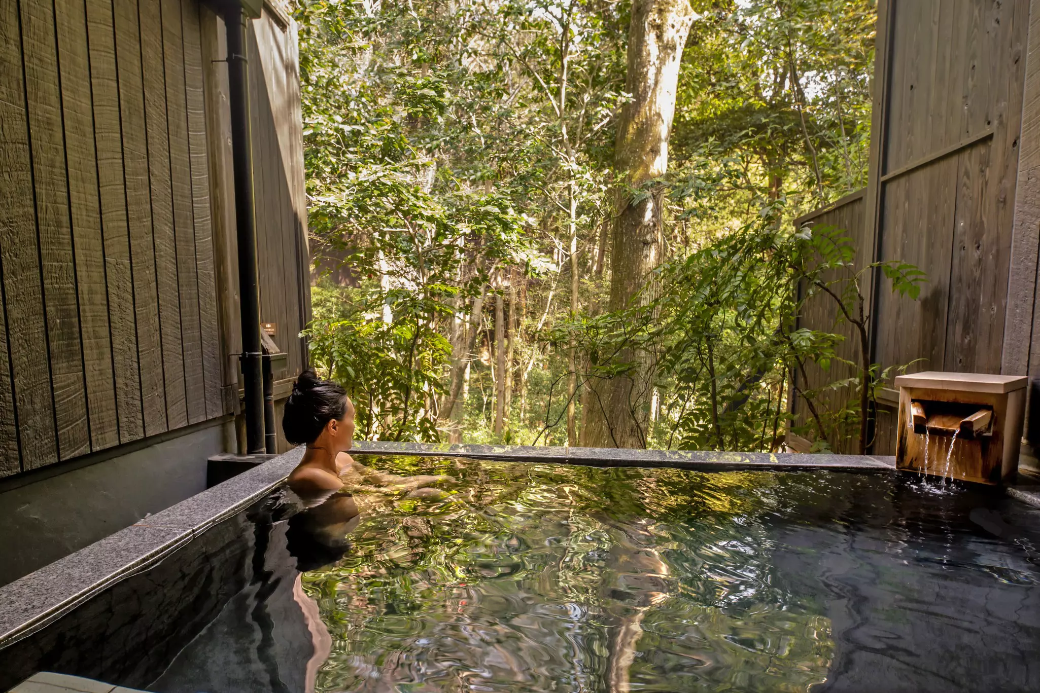 A woman relaxing in an open-air onsen pool in Hakone-Yumoto, Japan.